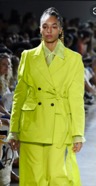 African American woman wearing a stylish yellow-green suit dress.