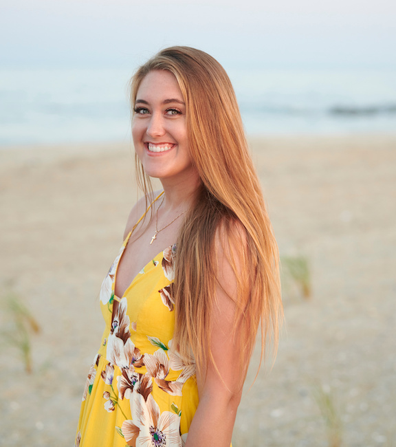 Blonde girl wearing a yellow dress on the beach.