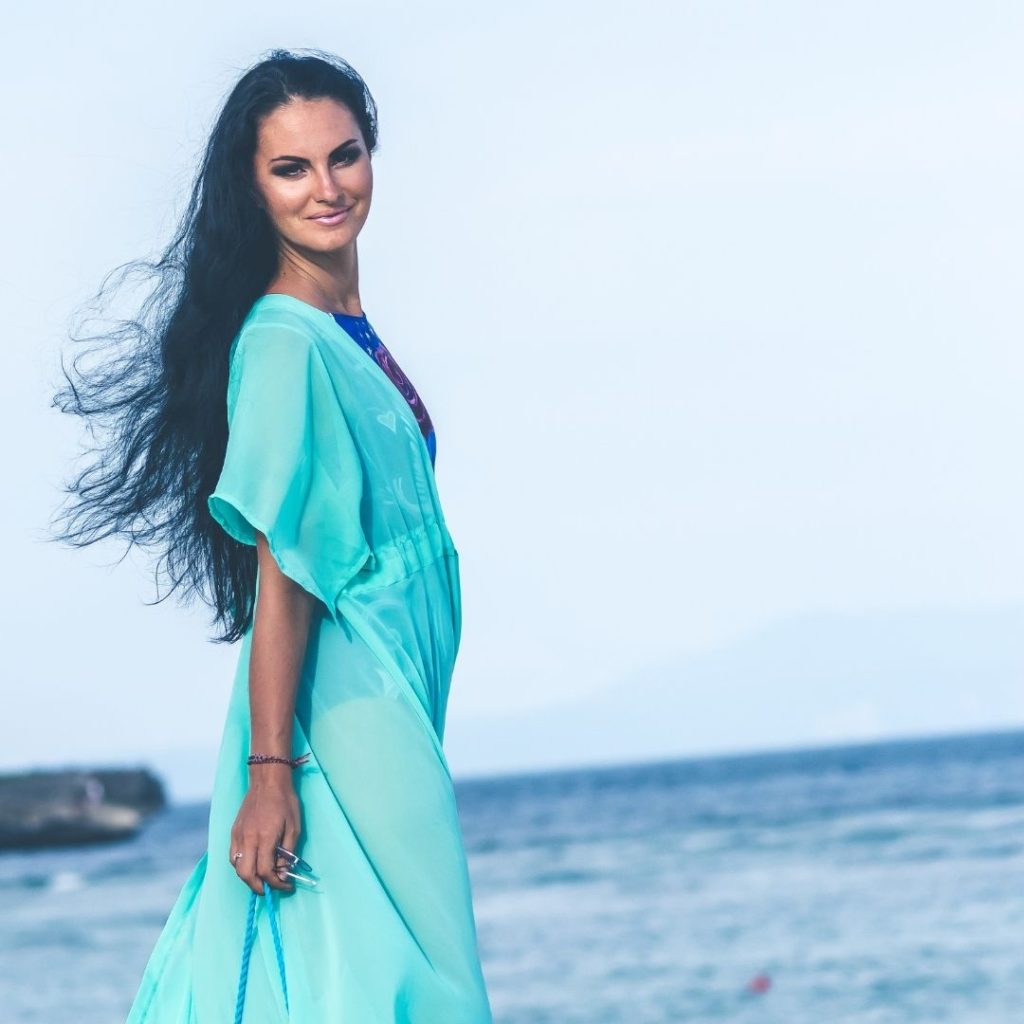 Woman in a turquoise dress with the ocean in the background.